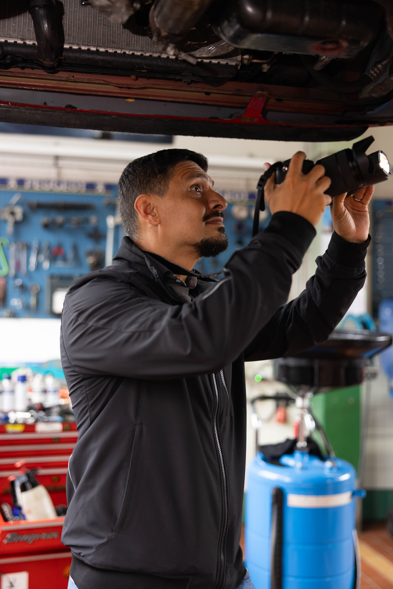 Hamed fotografiert in der Werkstatt die Unterseite eines Autos