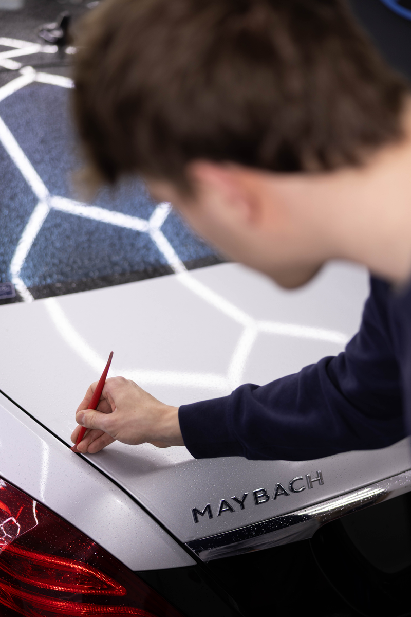 Nahaufnahme: an einem Maybach wird eine Linie für die Folierung angezeichnet